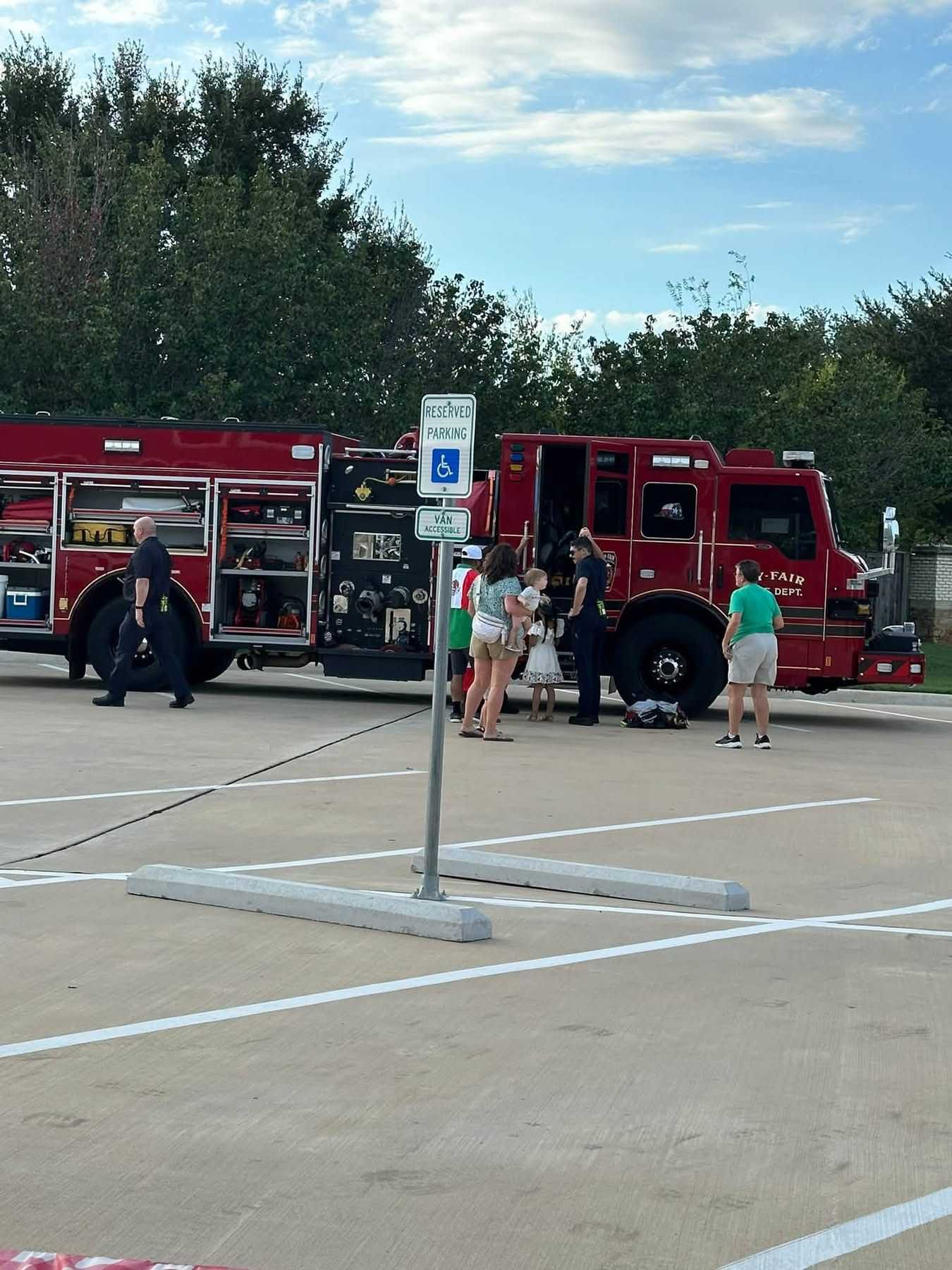 Families gather around an open Cy-Fair Fire Department fire engine at a community event, viewing emergency equipment and speaking with firefighters in a parking lot.